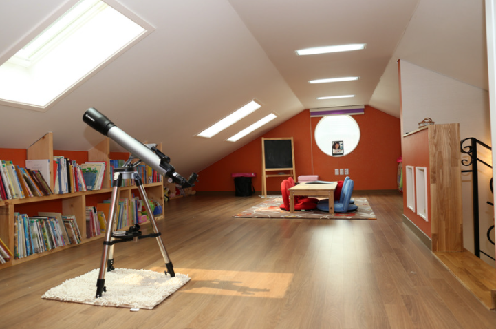 A child's dream attic space set up with books, a telescope, and craft area