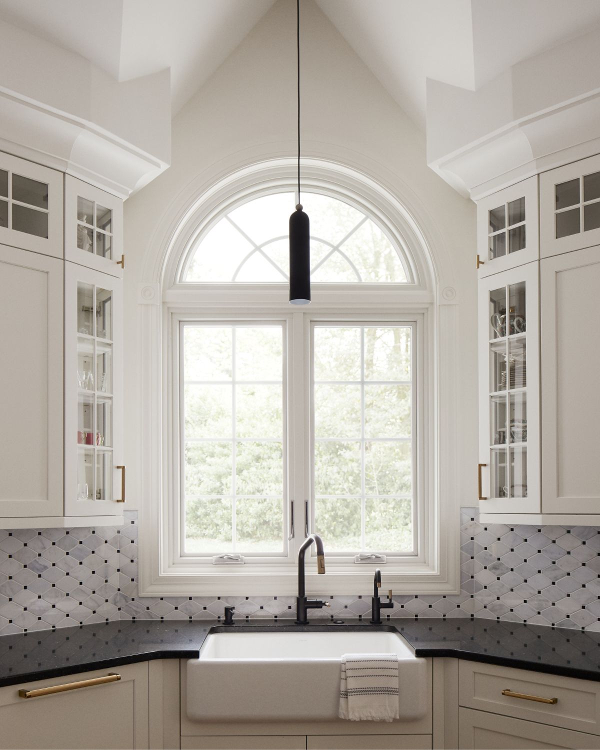 Custom white cabinetry surround a window above the sink of a newly renovated kitchen in Ambler.