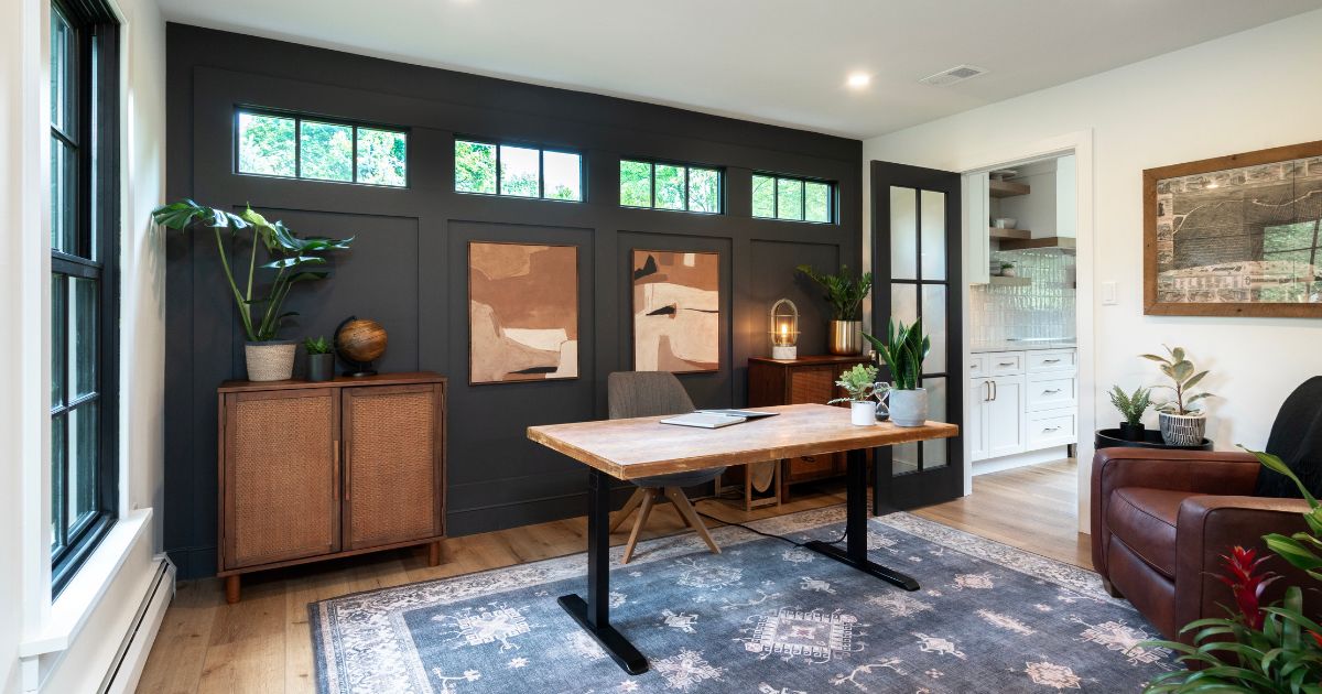 Home office with black painted focal wall and transom windows.