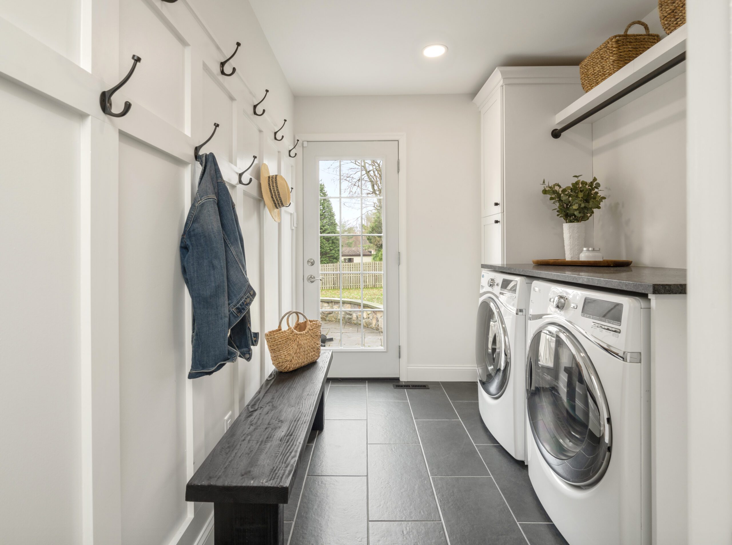Remodeled laundry room with black tile floor and paneled walls.