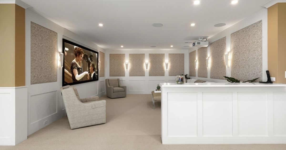 Custom paneled basement remodel with large screen TV on the wall.