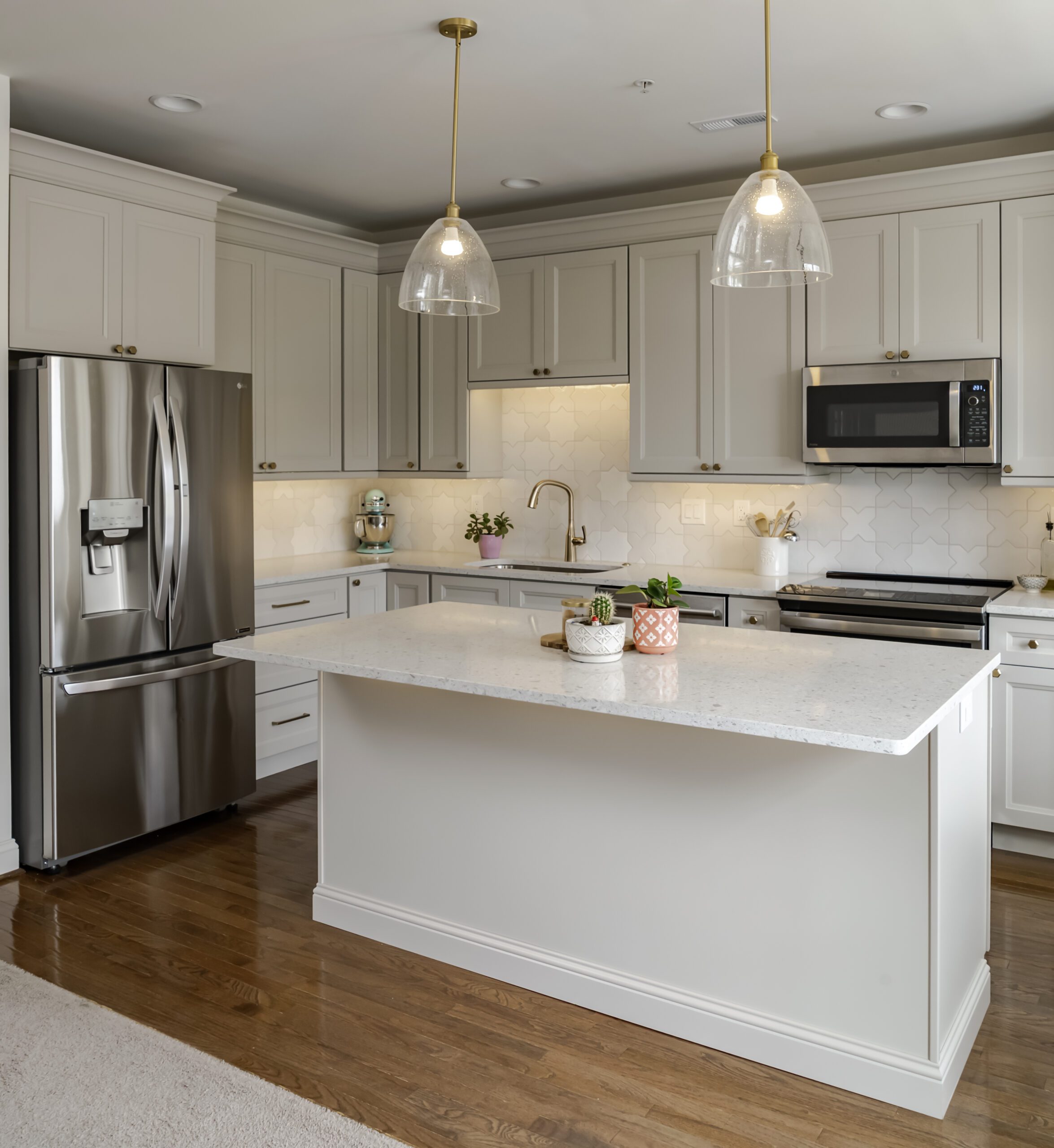 Remodeled kitchen with pale taupe cabinets. White quartz countertops