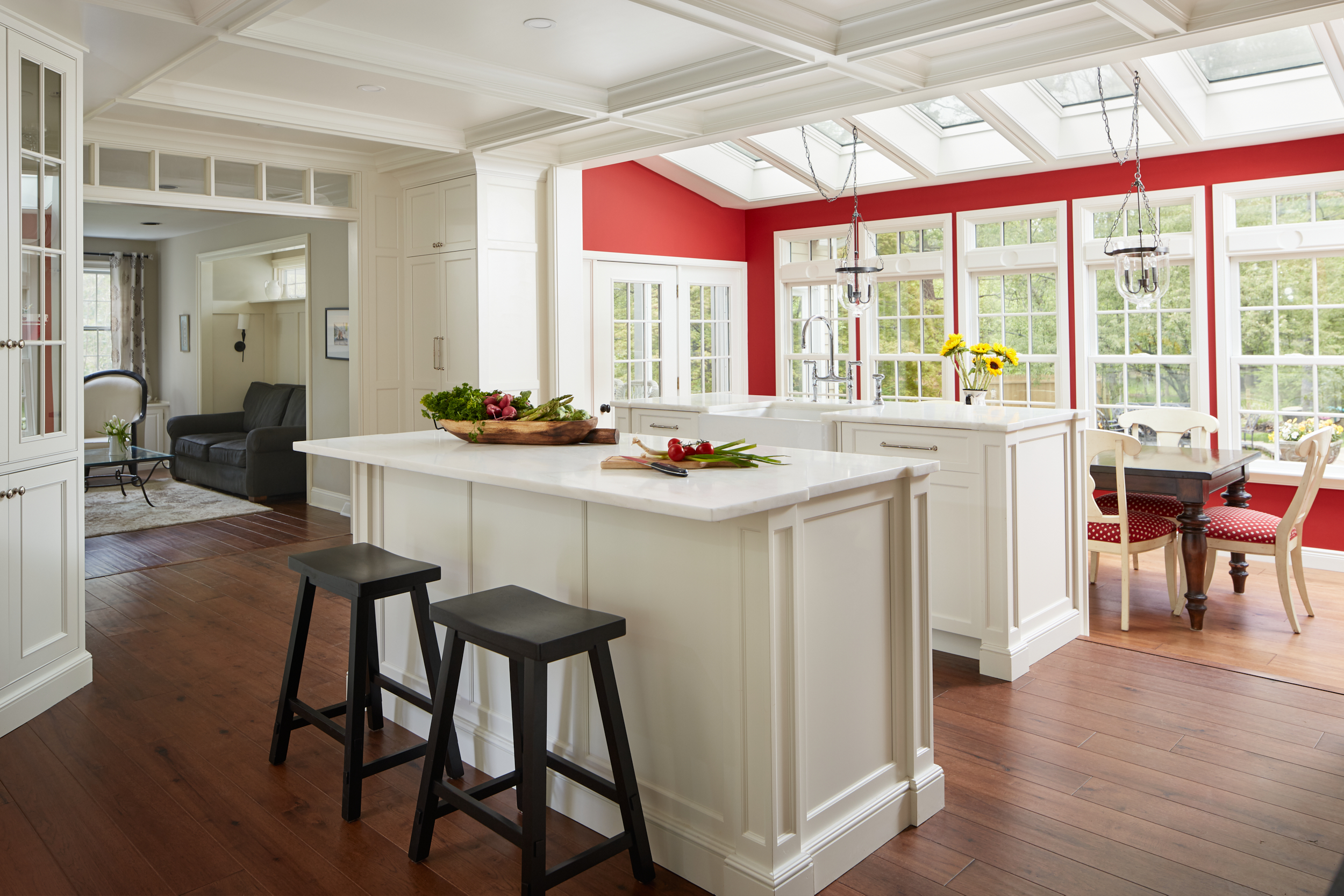 White double island in renovated kitchen with red painted accent wall and coffered ceilings
