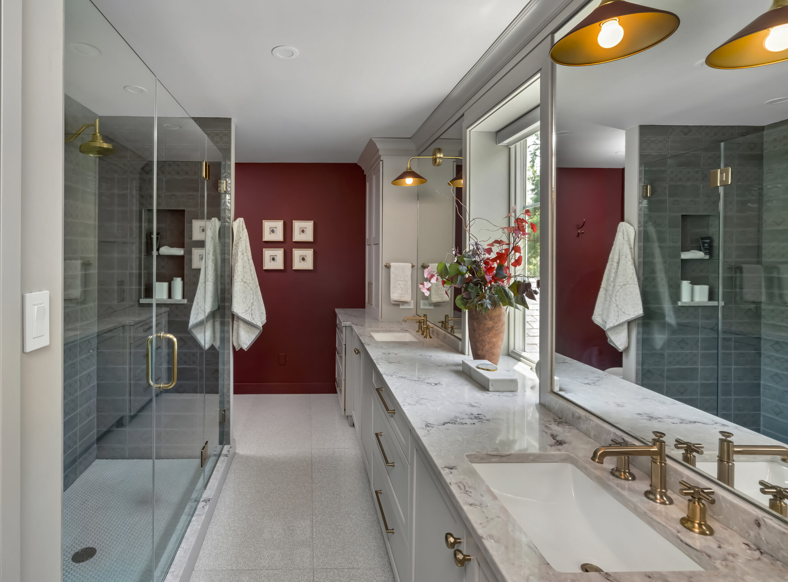 Red accent wall in primary renovated bathroom, with glass shower doors